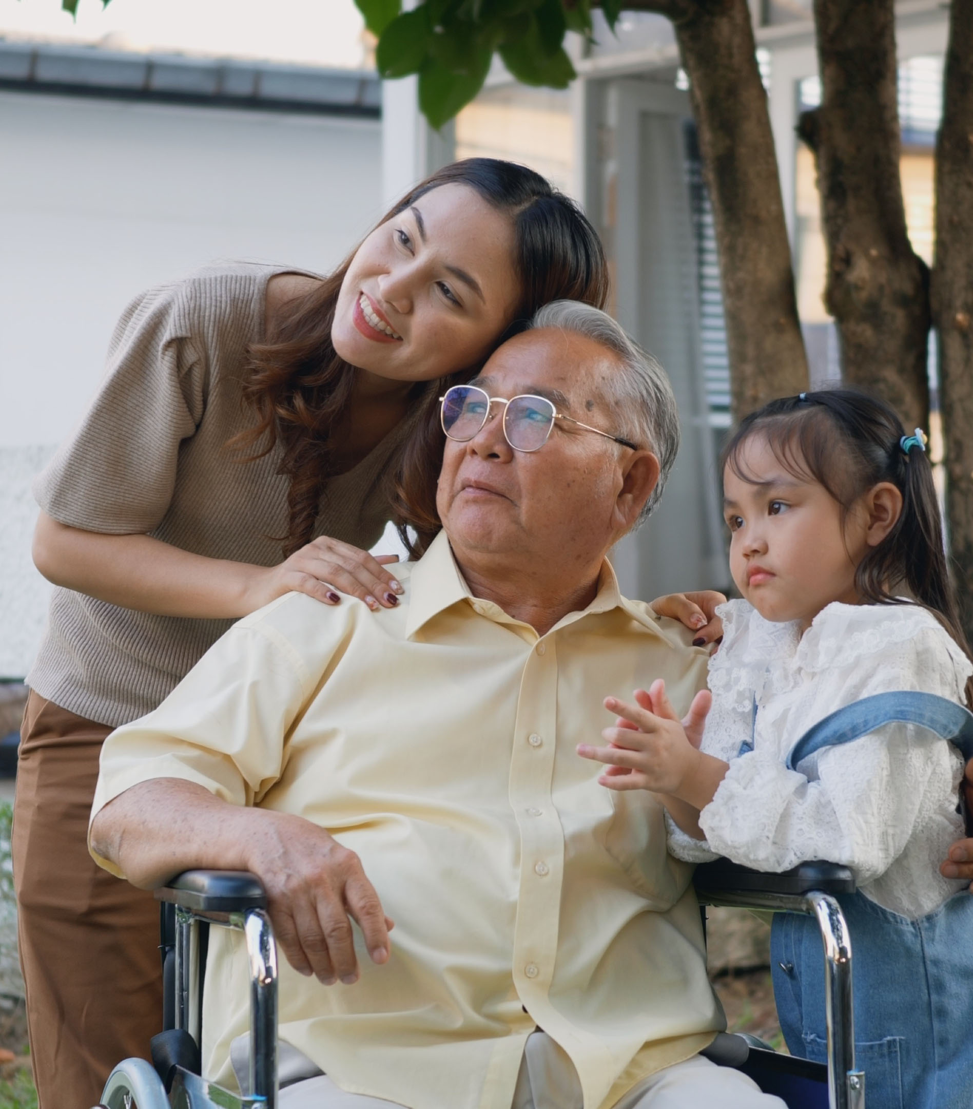 elderly man in wheelchair surrounded by woman and child