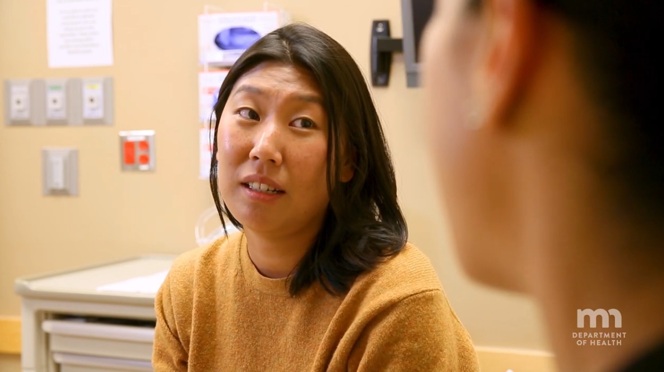a woman with short black hair and yellow sweater