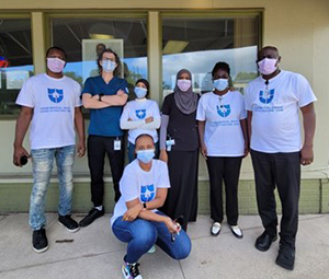 seven Odam Medical Group staff members wearing masks in front of the clinic