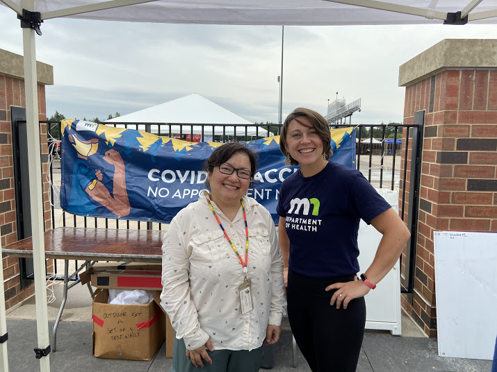 Two people standing in front of MDH COVID-9 banner