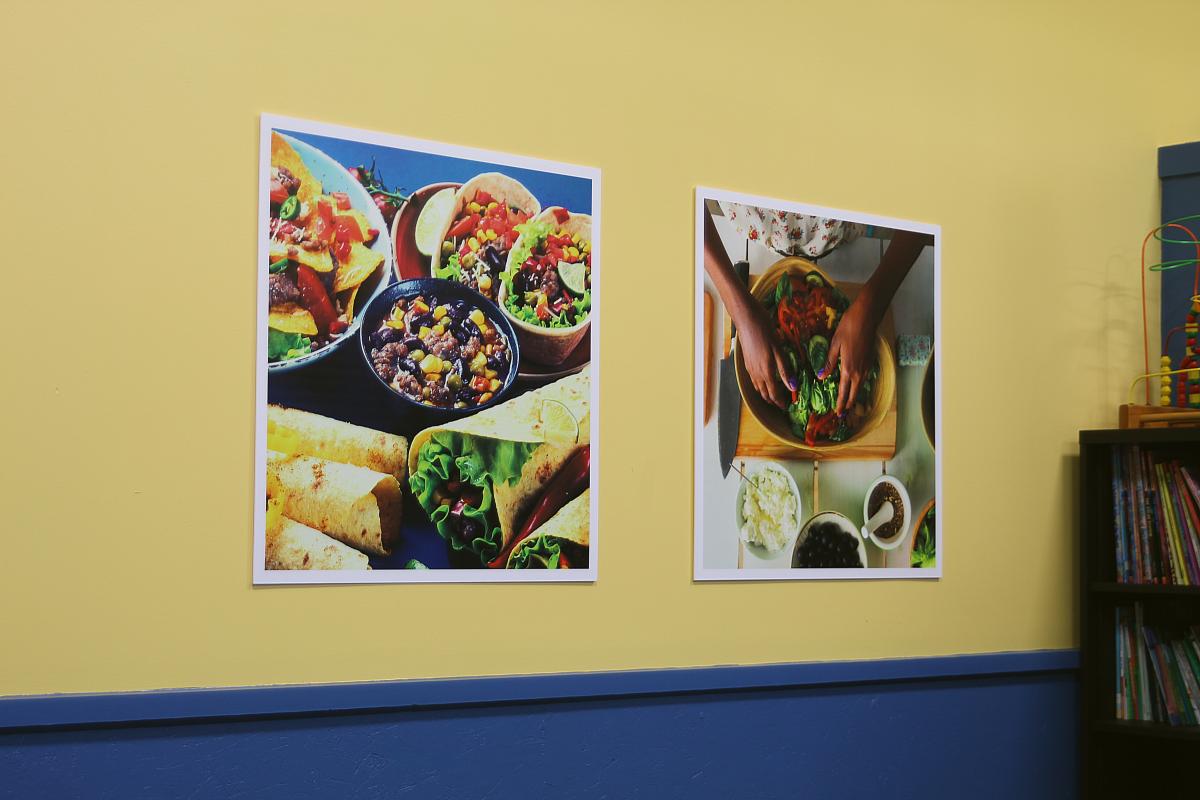 Two posters showing tacos and fresh food preparation on a yellow wall
